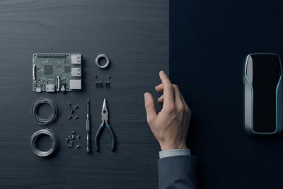 Workbench with loose components and tools on one side, a sleek finished device on the other, and a hand deciding between them