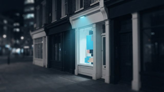 A small shop window lit by a cyan lamp on a dark street at night, standing out among the unlit storefronts