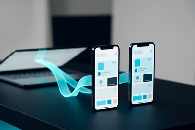 A single cyan light ribbon flowing from a laptop and reaching two different smartphones standing side by side