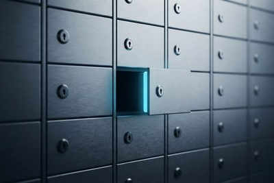 A wall of identical brushed-steel safe-deposit boxes with one drawer slid open and cyan light glowing from inside