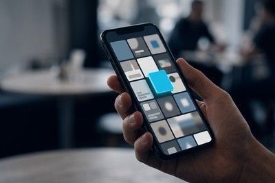 Hand holding a phone with a grid of app tiles where one cyan tile rises above the rest