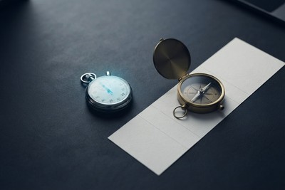 Stopwatch and a compass resting on a printed project timeline broken into three phases