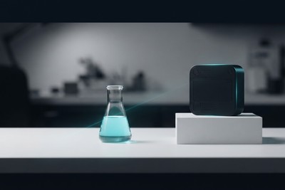 A glass lab flask of cyan liquid next to a sleek black device on a white plinth