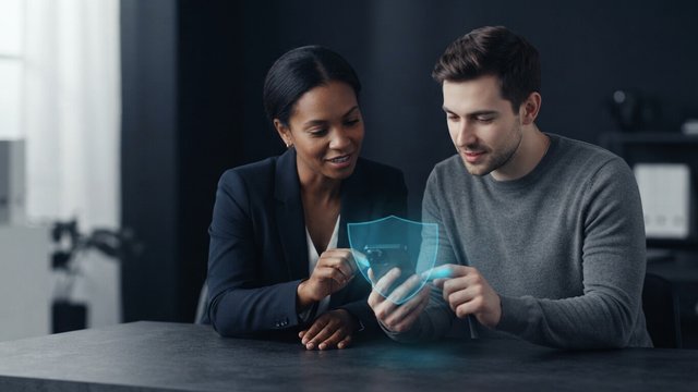 Two colleagues looking at a phone protected by a translucent cyan shield