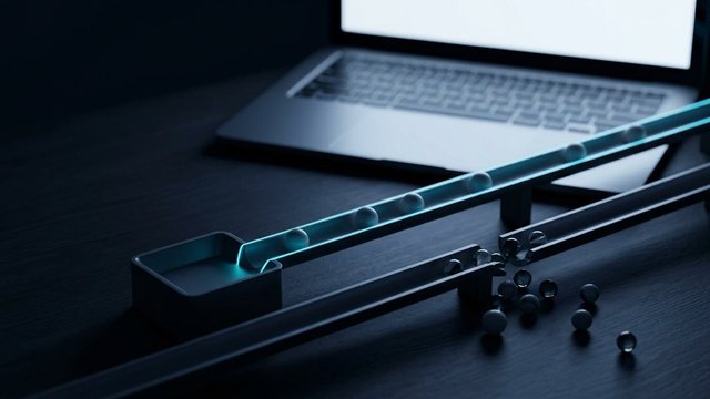 Marble run where marbles roll smoothly along a cyan-lit track while others spill off a broken section onto the desk